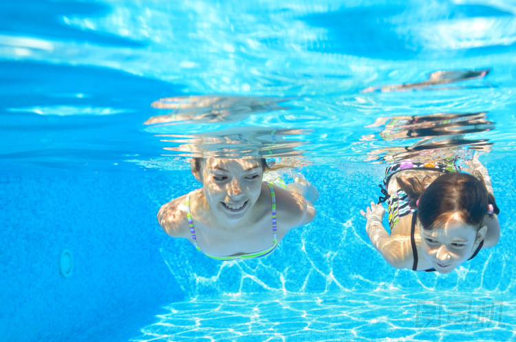 快樂女生水下在游泳池里游泳