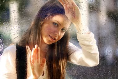 雨后窗戶附近的年輕女子圖片