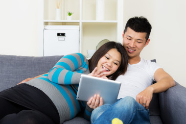 亞洲孕婦和她的丈夫在家里使用平板電腦