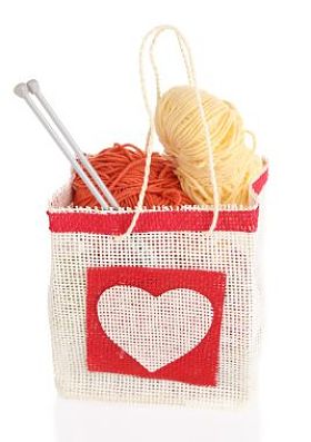 毛球的毛线和木制编织针在仿古工艺包上白色孤立