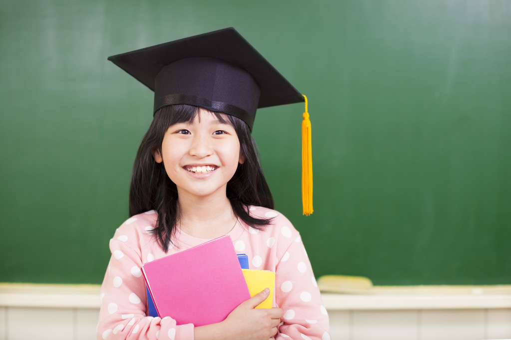 微笑女孩穿的毕业帽和拥有书籍 微笑女孩穿的毕业帽和拥有书籍