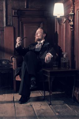 老式 1900年时尚男人的胡子和眼镜。坐在