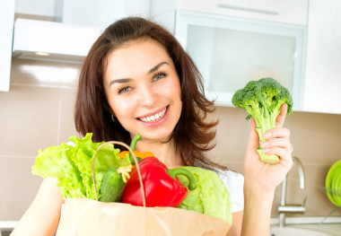 快樂的年輕女人與蔬菜的購物袋。飲食概念