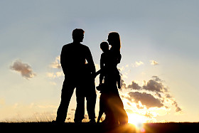 幸福的家庭和狗以外在日落时的剪影