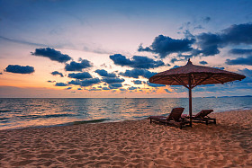 木制椅子和遮阳伞在沙滩上照片