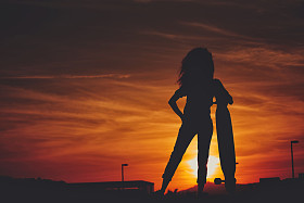 长板在夕阳的美丽女孩的剪影图片