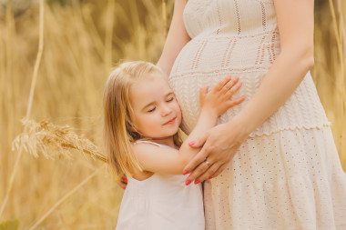 可愛的小女孩，親吻他懷孕的媽媽的肚子