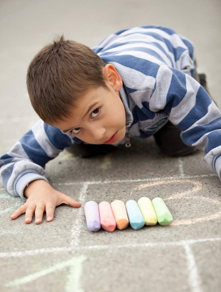 绘图用粉笔在户外的小男孩 绘图用粉笔在户外的小男孩