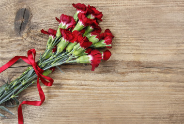 木制的背景上的紅色康乃馨花的香味。頂視圖