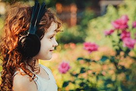 小女孩在耳机中夏公园上听音乐。我