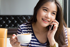 美丽的女人谈电话，拿着杯咖啡
