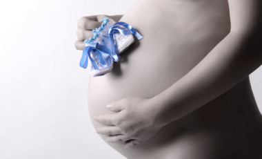 懷孕的婦女抱著她的手兩個(gè)嬰兒鞋