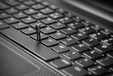 檢查筆記本電腦的小型警察。盜版、 互聯(lián)網(wǎng)黑客概念