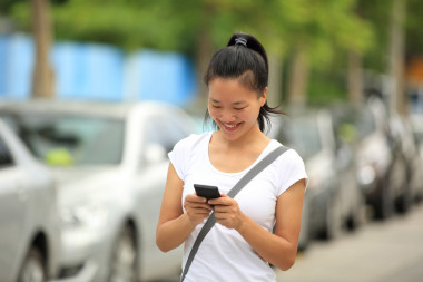 女人用她的手機走在停車場