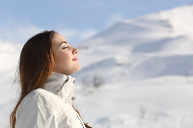 資源管理器中女人呼吸新鮮的空氣在冬天在一座雪山