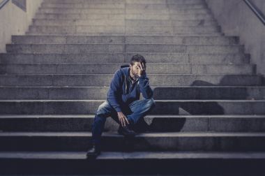 年輕人失去了坐在地上街頭的水泥樓梯上的凹陷