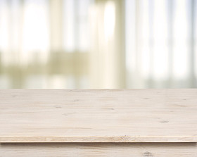 带窗帘背景的离焦窗上的木制桌子