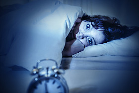 女人在床上用眼睛打开痛苦失眠和睡眠障碍