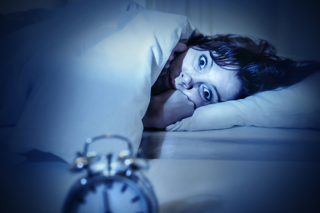 女人在床上用眼睛打开痛苦失眠和睡眠障碍
