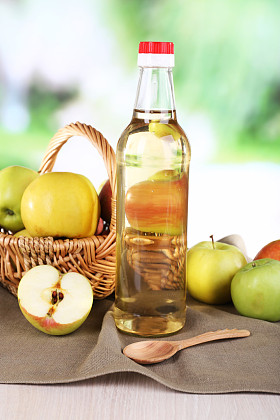 苹果醋玻璃瓶和成熟的新鲜苹果，木制的桌子，对自然背景上