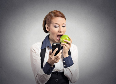 女人看著智能手機(jī)吃蘋果