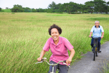 快樂(lè)亞洲老年人情侶在公園里騎自行車