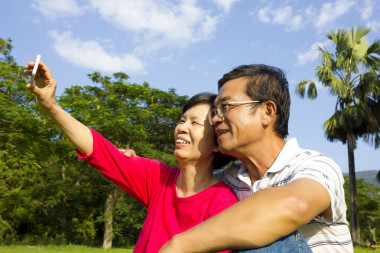 年長的夫婦坐在草地和拍照
