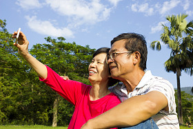 年长的夫妇坐在草地和拍照