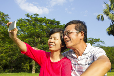年長的夫婦坐在草地和拍照