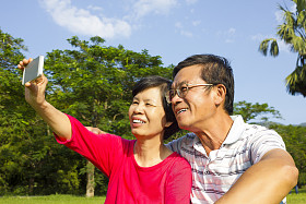 年长的夫妇坐在草地和拍照