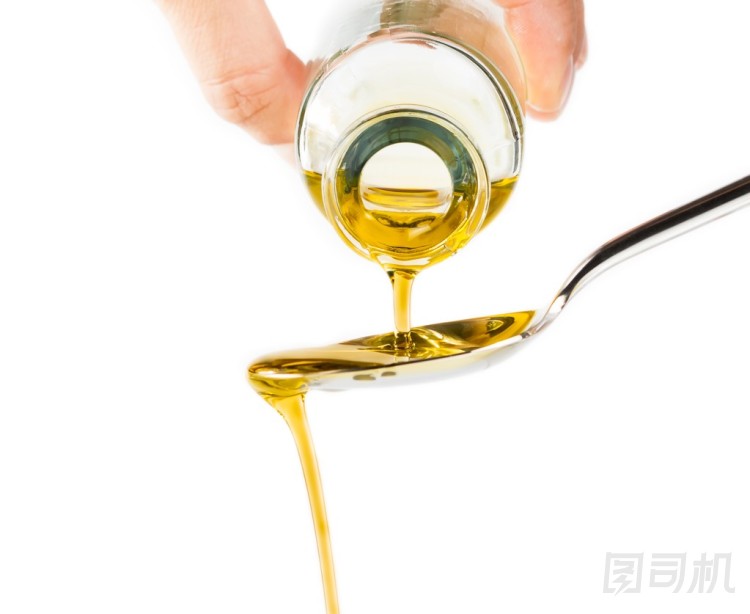 瓶特級(jí)初榨橄欖油潑孤立在白色背景上的勺子