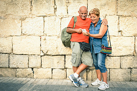 Happy senior couple with modern smart phones -- concept active seniors and new technology with interaction -- travel lifestyle fun without age limit