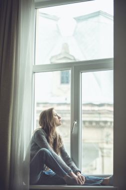 美麗的年輕女子坐在窗邊圖片