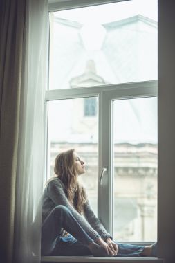 美丽的年轻女子坐在窗边图片
