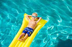 男孩在黄色的筏子上的游泳池里放松和娱乐