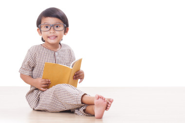 可愛的男孩正在讀一本書，戴著眼鏡