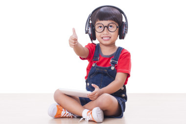 快樂的男孩，戴著耳機(jī)連接到一臺(tái)平板電腦