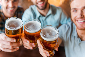 举杯同啤酒的年轻男子在酒吧
