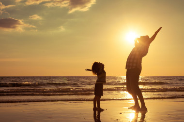 父親和兒子在日落的時候在海灘上玩