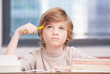 小學(xué)男孩在教室的課桌上，試圖尋找新的想法