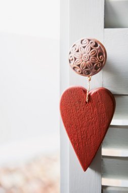 白色阳台窗户上挂的红色木心照片