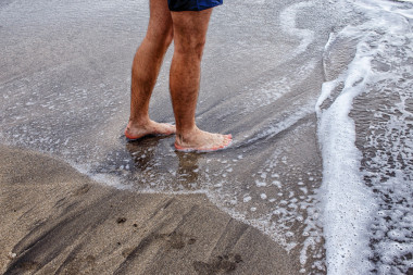 男性的腳在沙灘上