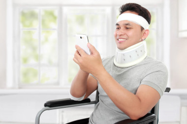 受傷的年輕人在輪椅上他 smartphione 播放