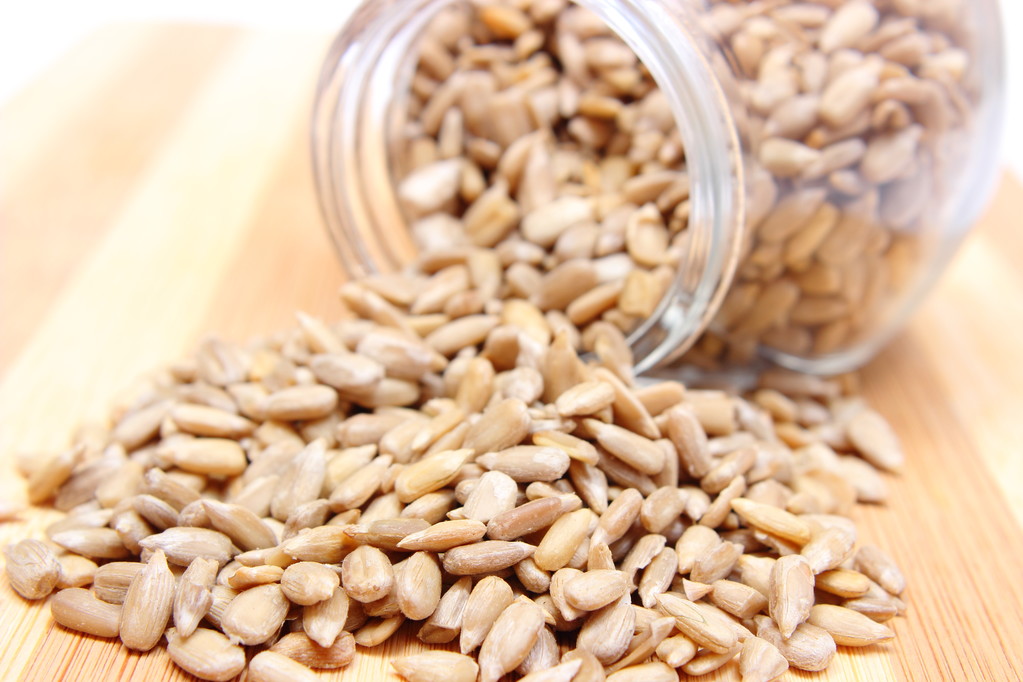 木制切菜板上的玻璃罐子里的向日葵种子大堆 木制切菜板上的玻璃罐子里的向日葵种子大堆