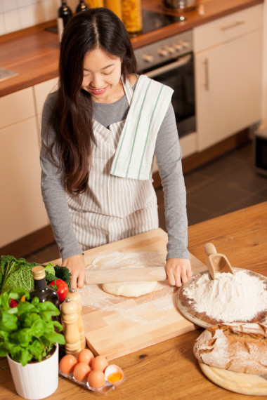 亞洲的年輕女人在她家的廚房里烤面包