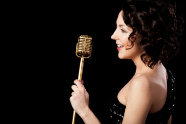 美麗的黑發(fā)女孩歌手唱歌與持有黃金的微笑