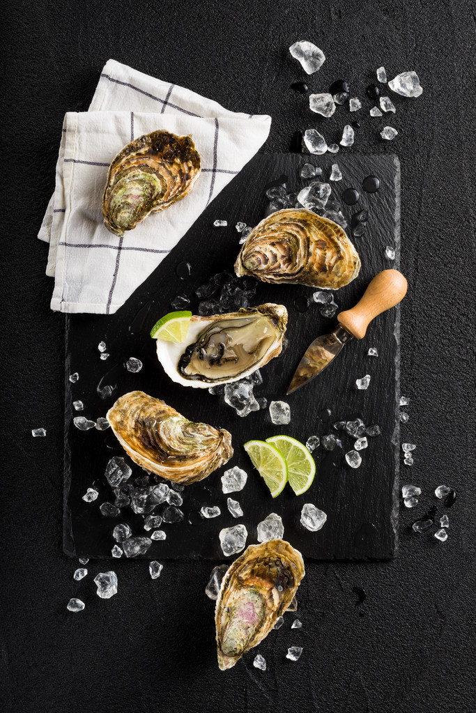 在一块黑色的石头上新鲜牡蛎板顶视图 在一块黑色的石头上新鲜牡蛎板顶视图