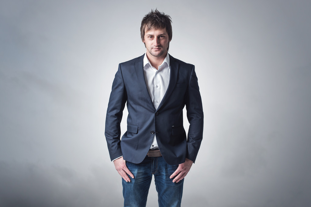 年轻的坚强和自信的男人正站，戏剧性的背景 skyclouds