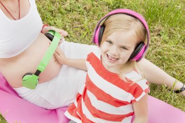 耳機(jī)和懷孕的媽媽的女孩