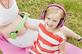 耳机和怀孕的妈妈的女孩